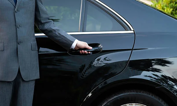 Chauffeur ouvrant la portière d'une berline noire