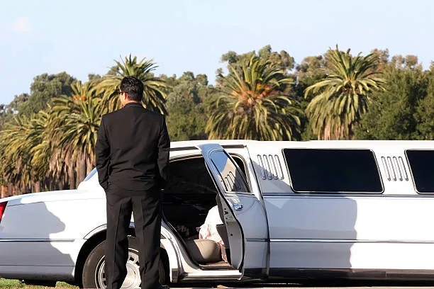 Chauffeur devant une limousine blanche